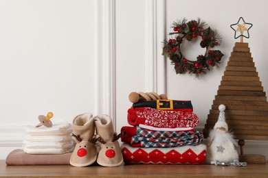 Photo of Baby clothes, accessories and Christmas decor on wooden table