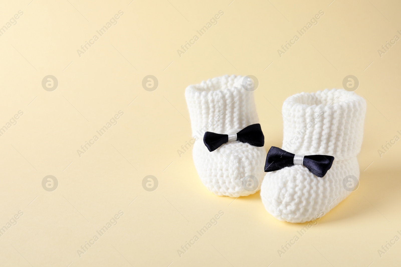 Photo of Handmade baby booties on color background. Space for text