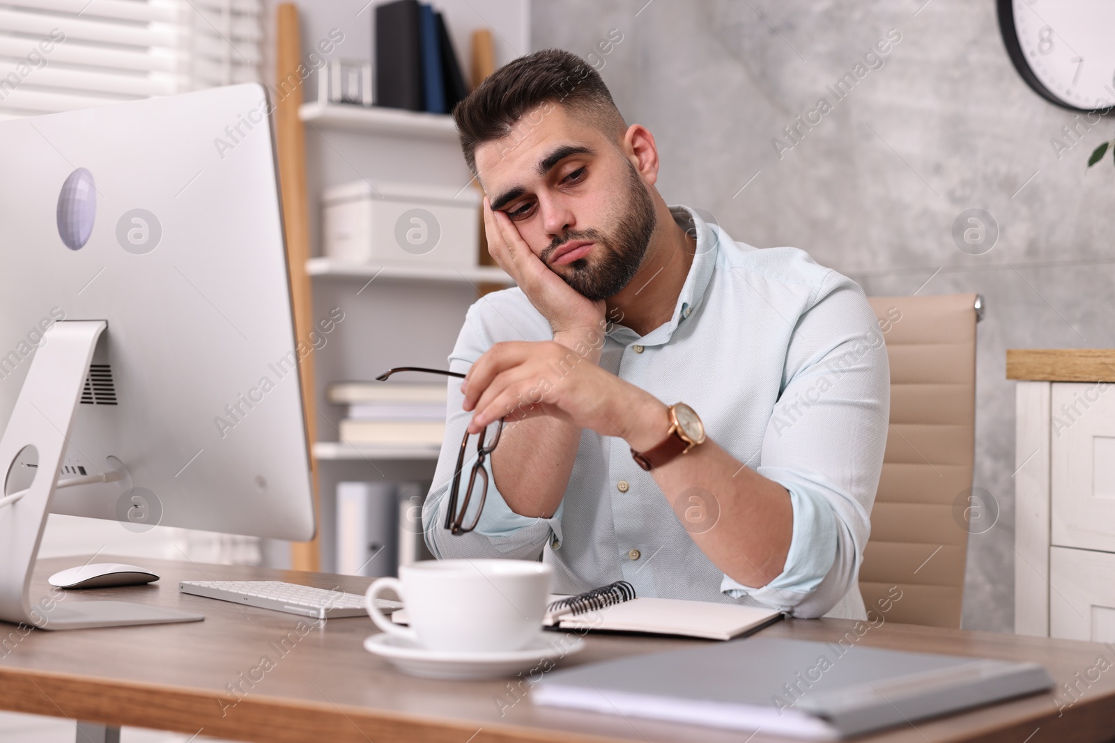 Photo of Overwhelmed man with glasses sitting at table in office