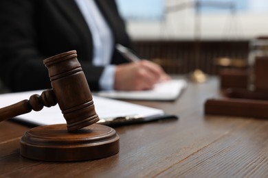 Photo of Lawyer working with documents at wooden table indoors, focus on gavel