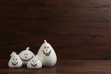 Image of White pumpkin shaped candle holders on wooden background, space for text. Halloween decoration