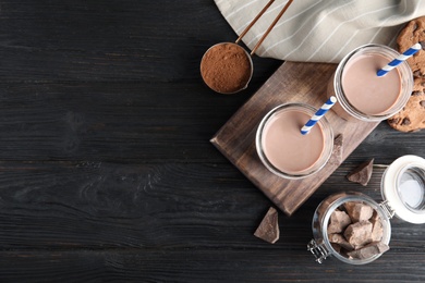 Flat lay composition with jars of tasty chocolate milk and space for text on wooden background. Dairy drink