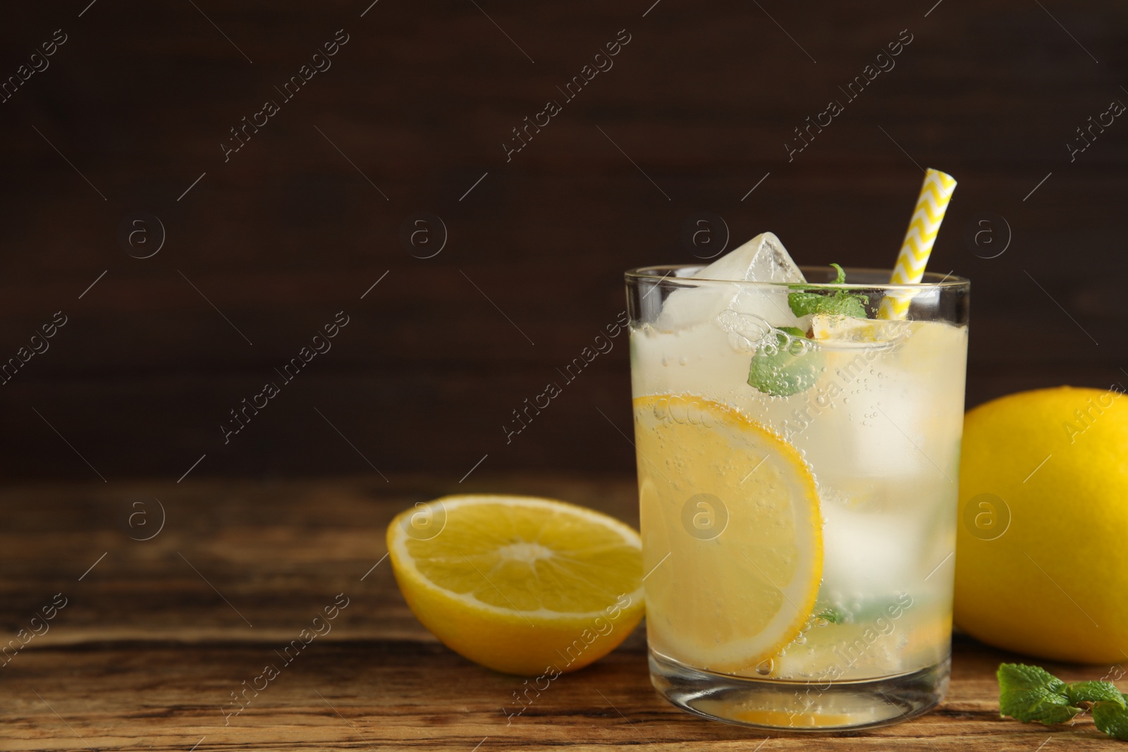 Photo of Cool freshly made lemonade in glass on wooden table. Space for text