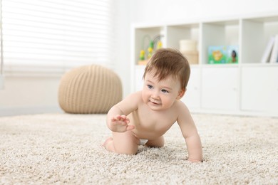 Cute baby boy crawling on carpet at home