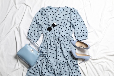 Flat lay composition with stylish blue dress on white fabric