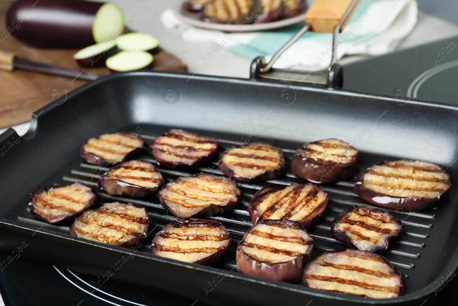 Photo of Delicious grilled eggplant slices in pan on stove, closeup