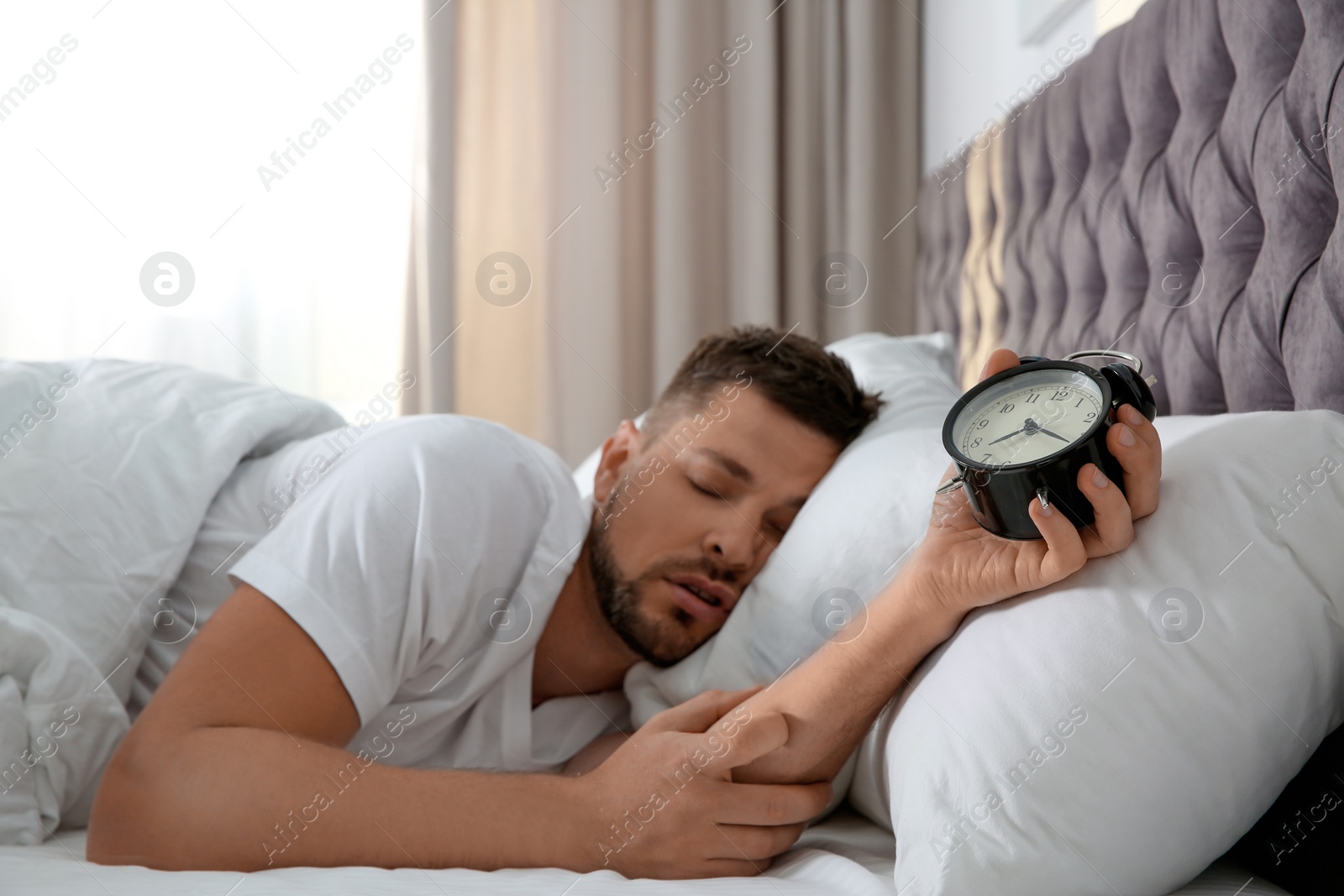 Photo of Man with alarm clock sleeping at home in morning