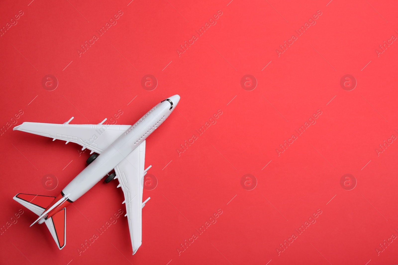 Photo of Toy airplane on red background, top view. Space for text