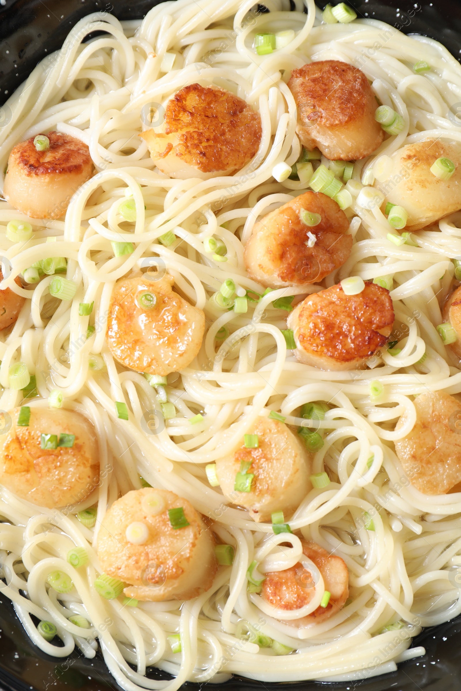 Photo of Delicious scallop pasta with green onion in pan, top view