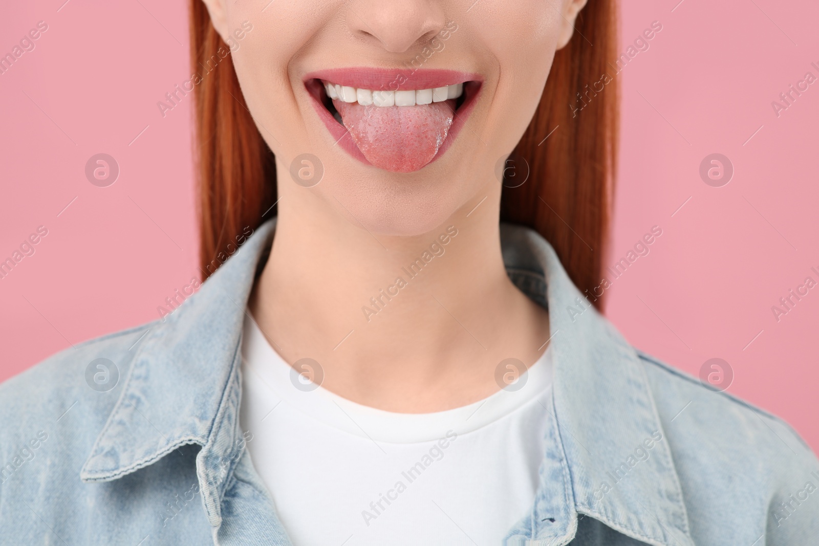 Photo of Happy woman showing her tongue on pink background, closeup