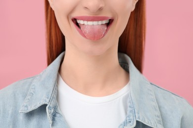 Happy woman showing her tongue on pink background, closeup