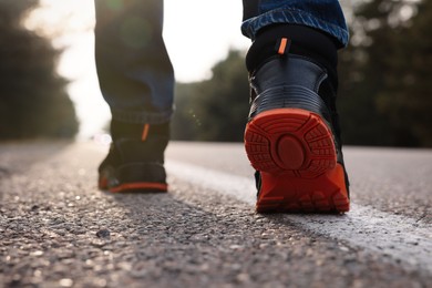 Man going along road, closeup of legs