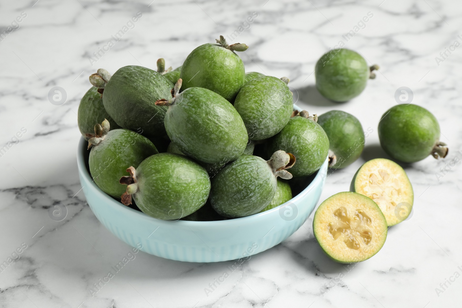 Photo of Fresh green feijoa fruits on white marble table, closeup