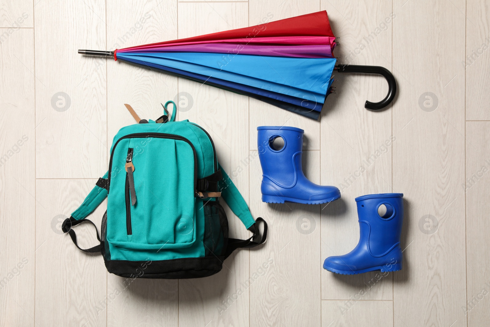 Photo of Flat lay composition with umbrella, backpack and rubber boots on wooden background