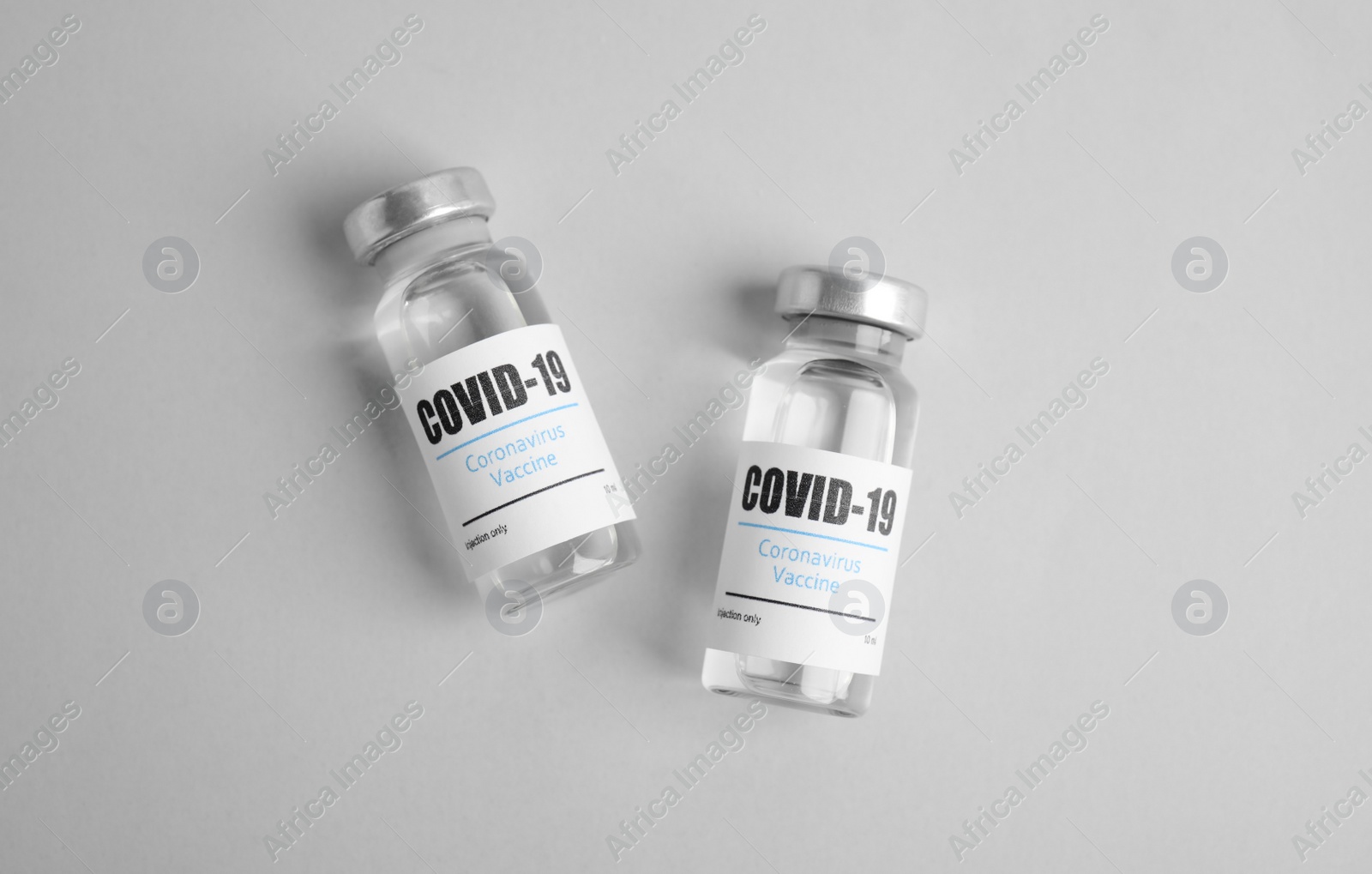 Photo of Vials with coronavirus vaccine on light background, flat lay