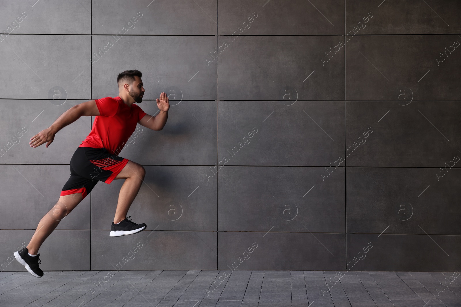 Photo of Young man running near building outdoors. Space for text