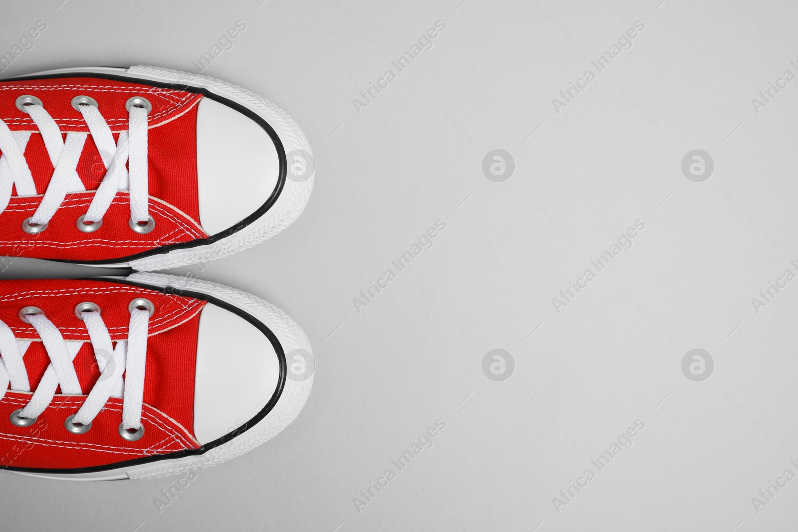 Photo of Pair of new stylish red sneakers on light grey background, flat lay. Space for text