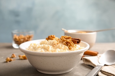 Photo of Creamy rice pudding with cinnamon and walnuts in bowl served on table. Space for text