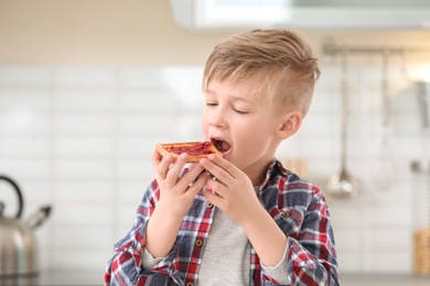 Photo of Cute little boy eating tasty toasted bread with jam in kitchen