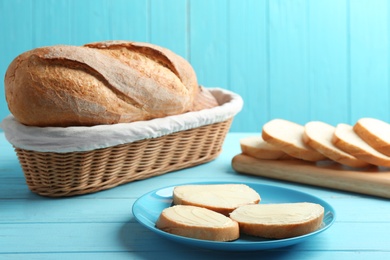 Tasty fresh bread with butter on light blue wooden table