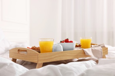 Photo of Good morning. Tray with tasty breakfast on bed at home