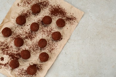 Photo of Delicious chocolate candies powdered with cocoa on light table, flat lay. Space for text