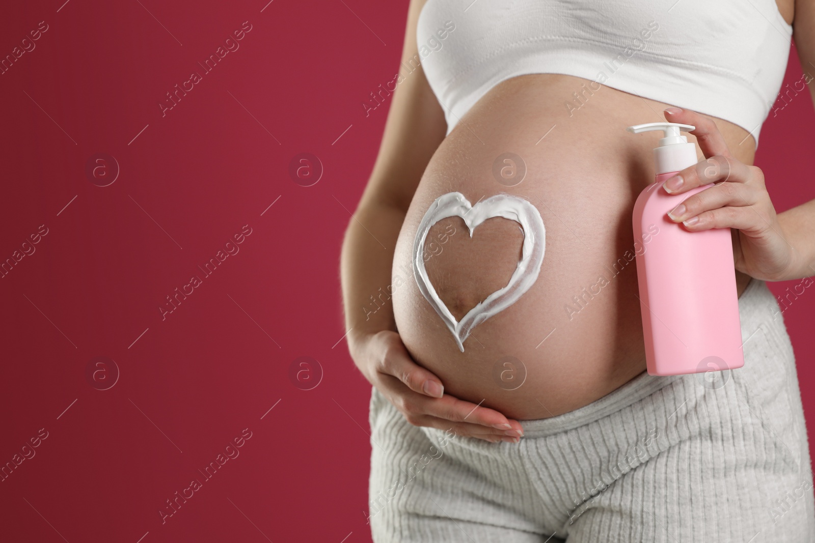 Photo of Young pregnant woman with cosmetic product on pink background, closeup. Space for text