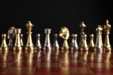 Many chess pieces on wooden checkerboard against black background, selective focus