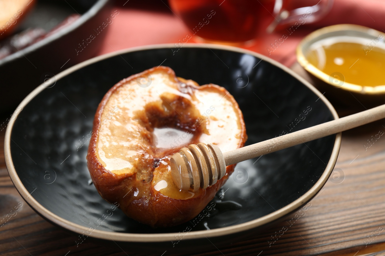 Photo of Tasty baked quince with honey in bowl on wooden table, closeup