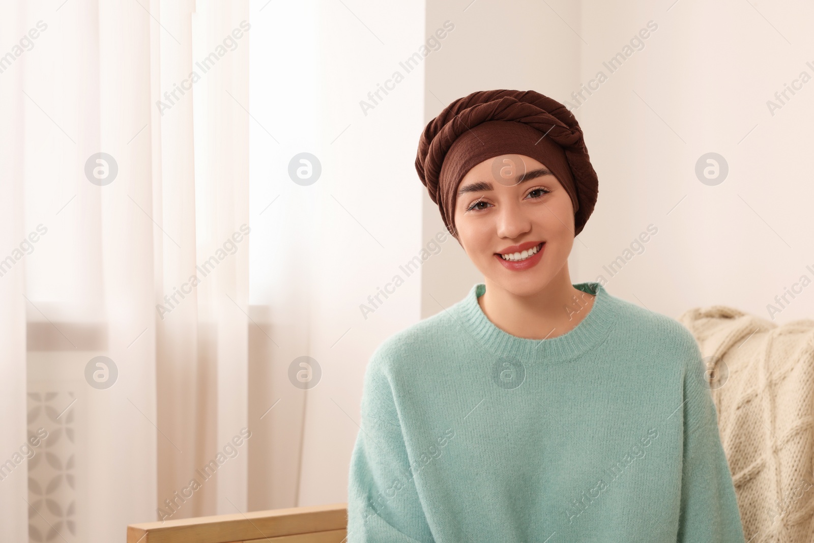 Photo of Cancer patient. Young woman with headscarf near window indoors, space for text