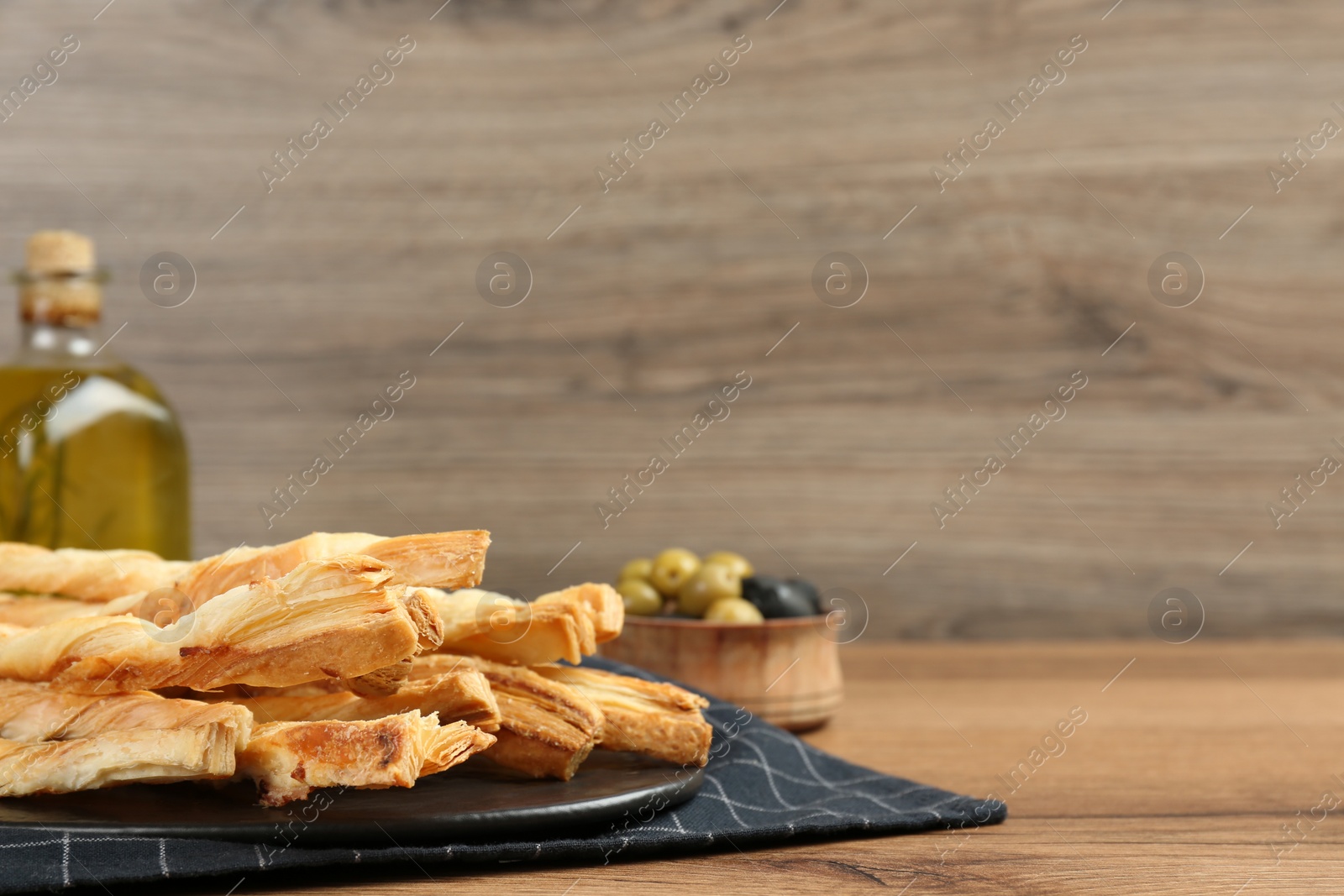 Photo of Tasty grissini and olives on wooden table, space for text