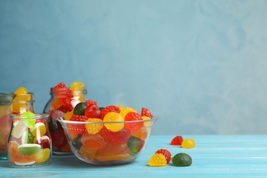 Delicious gummy candies on light blue wooden table. Space for text