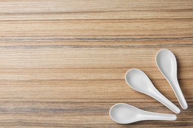 Miso soup spoons on wooden table, flat lay. Space for text