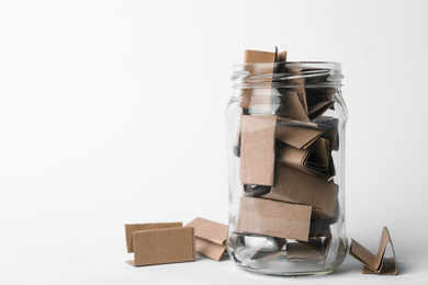 Photo of Glass jar full of brown paper sheets on white background