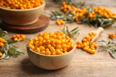 Photo of Ripe sea buckthorn berries on wooden table