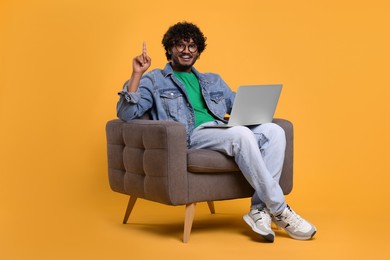 Photo of Smiling man with laptop sitting in armchair on yellow background