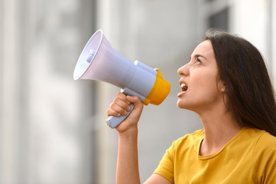 Image of Emotional young woman with megaphone outdoors. Protest leader