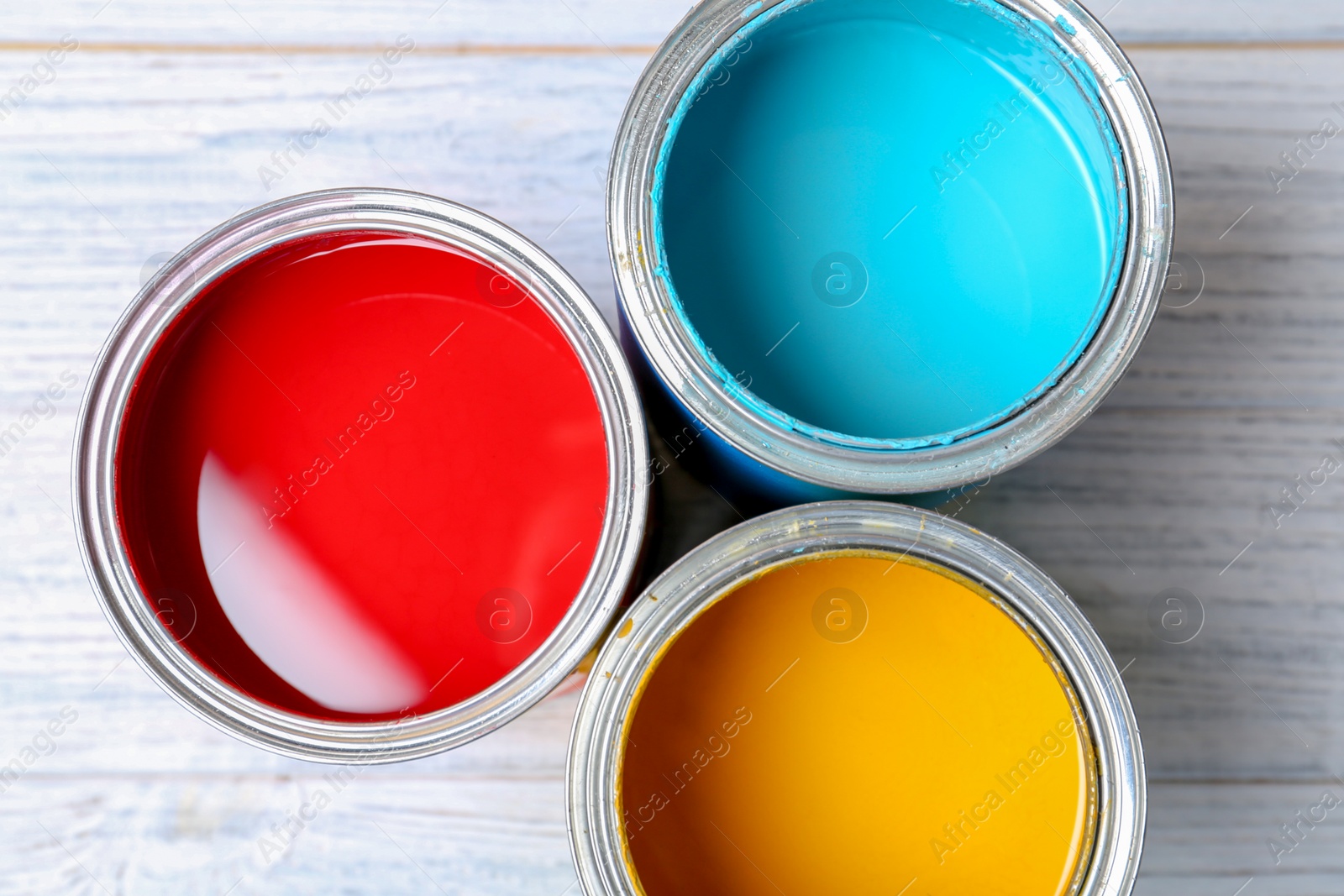 Photo of Tin cans with paint on wooden background, top view