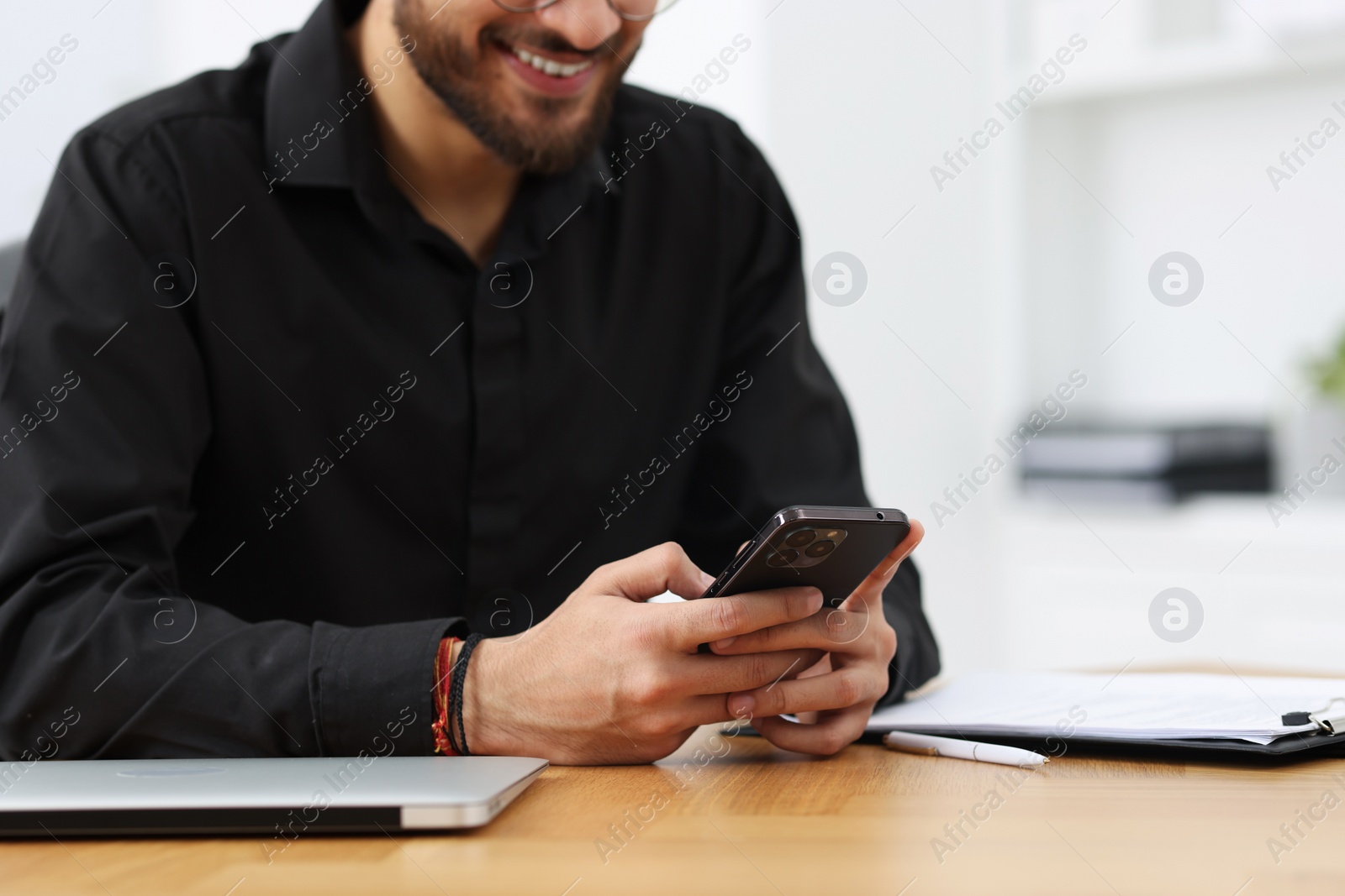 Photo of Man using smartphone at table in office, closeup