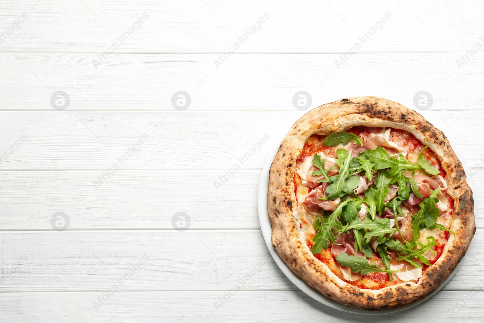 Photo of Tasty pizza with meat and arugula on white wooden table, top view. Space for text