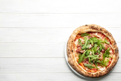 Photo of Tasty pizza with meat and arugula on white wooden table, top view. Space for text