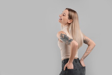 Photo of Portrait of beautiful tattooed woman on gray background, space for text