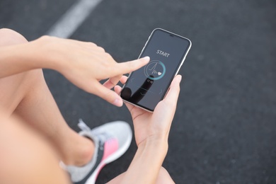 Photo of Young woman using fitness app on smartphone at stadium, closeup