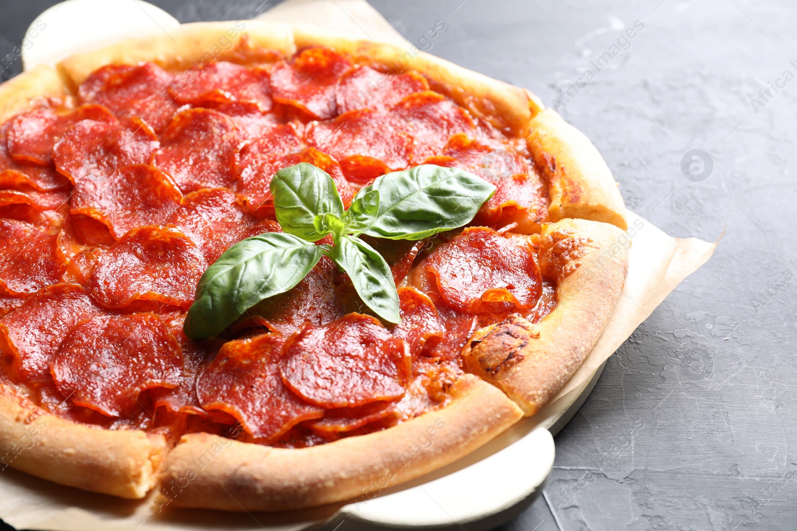 Photo of Tasty pepperoni pizza on dark grey table, closeup. Space for text