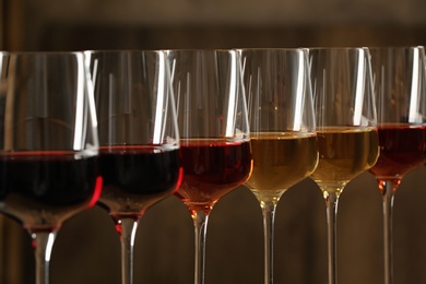 Photo of Glasses of different wines against blurred background, closeup. Expensive collection