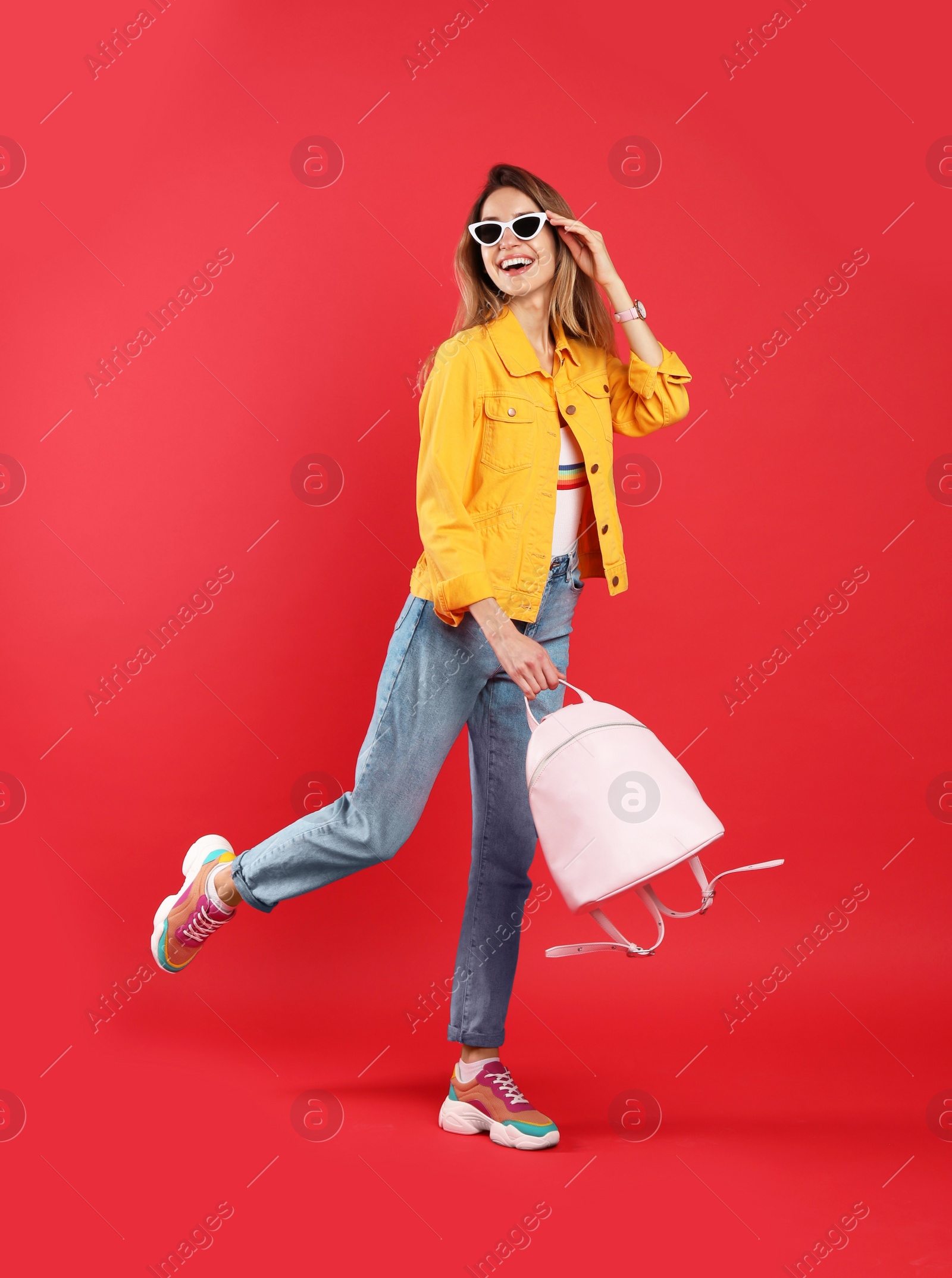 Photo of Happy woman with backpack on red background