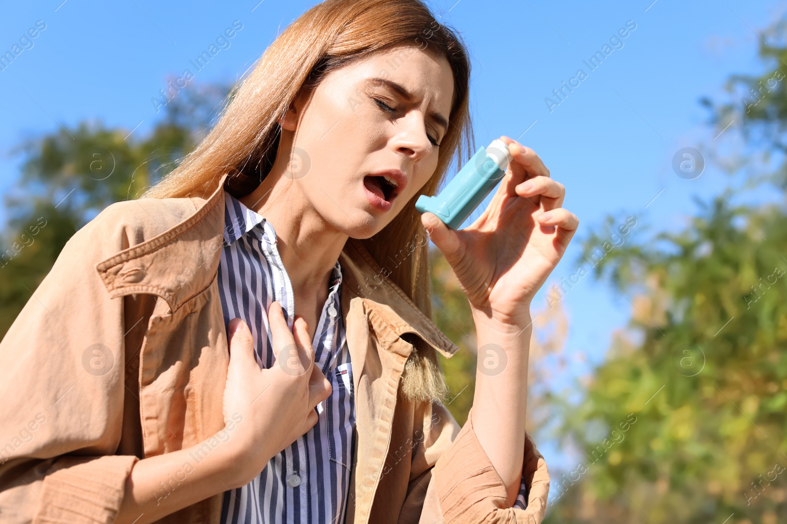 Photo of Woman using asthma inhaler outdoors. Space for text