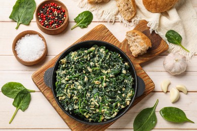 Photo of Tasty spinach dip with eggs in dish served on light wooden table, flat lay