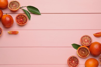 Photo of Many ripe sicilian oranges and leaves on pink wooden table, flat lay. Space for text