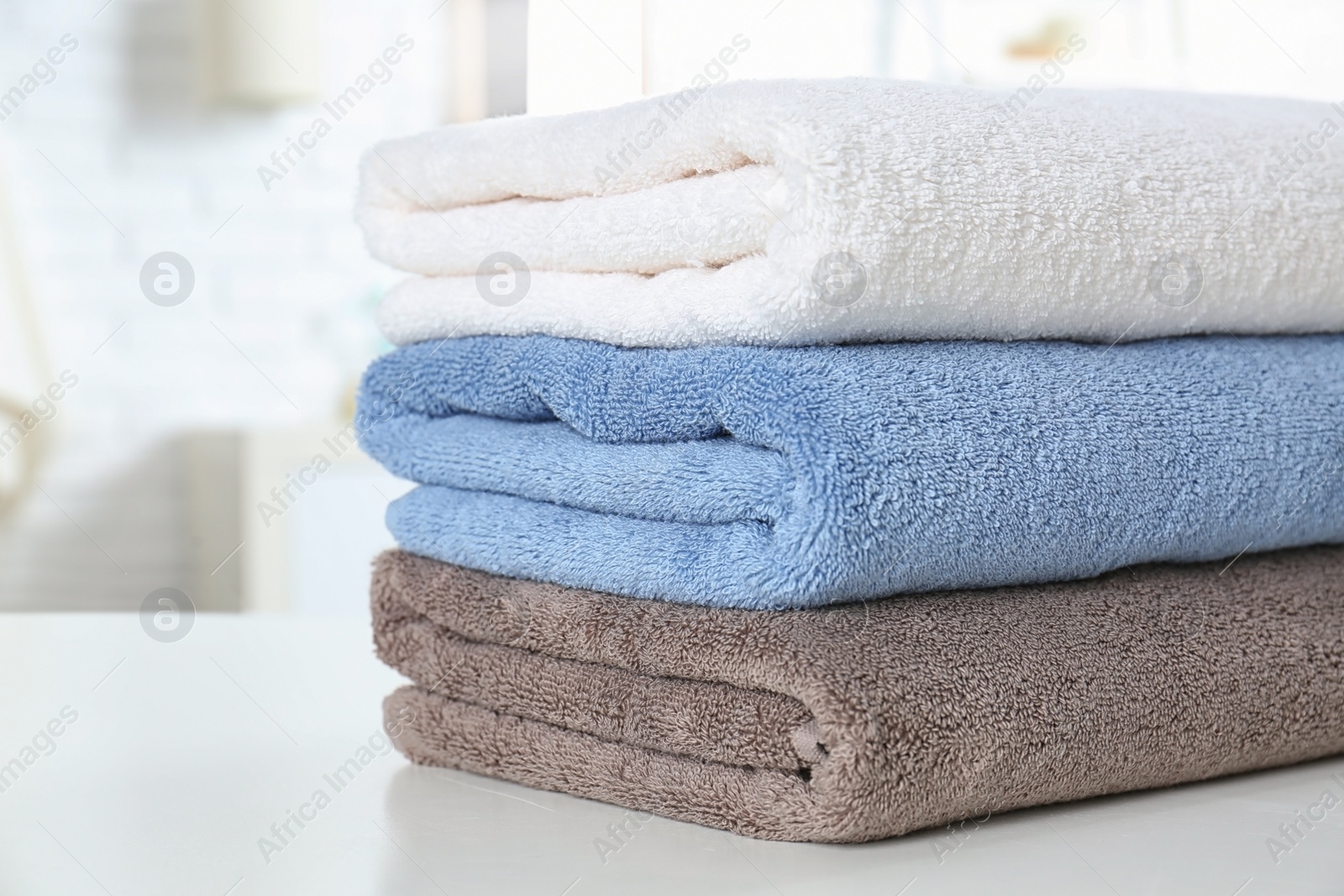 Photo of Stack of fresh towels on table in bathroom, closeup